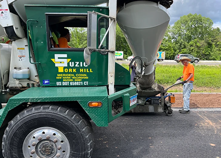 Roadwork crew paving a roadway with Suzio York Hill asphalt and crushed stone materials